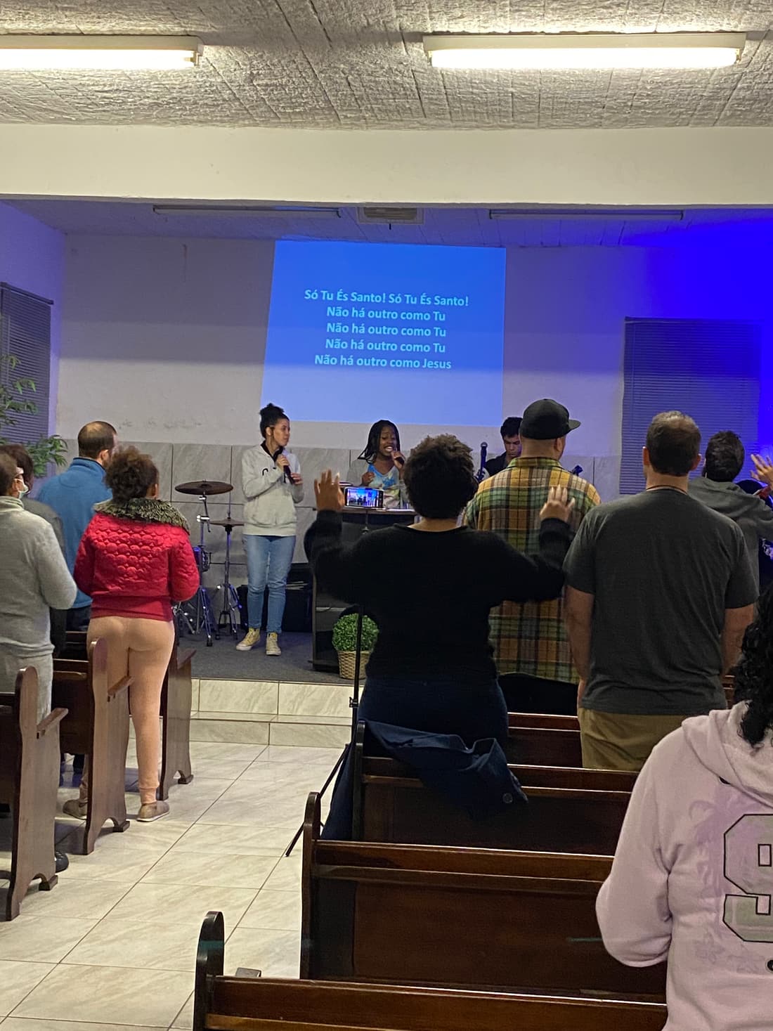 Worshippers gathered in the sanctuary of Casa de Jesus, lyrics projected on the wall
