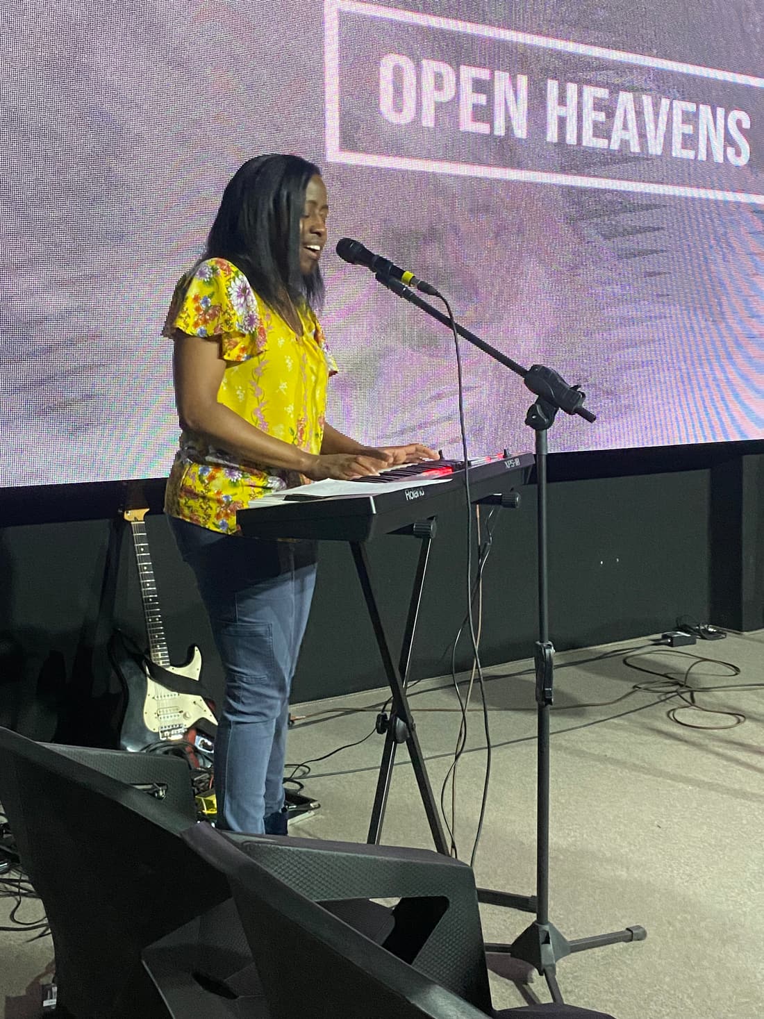 A worship leader singing and playing keyboard on stage
